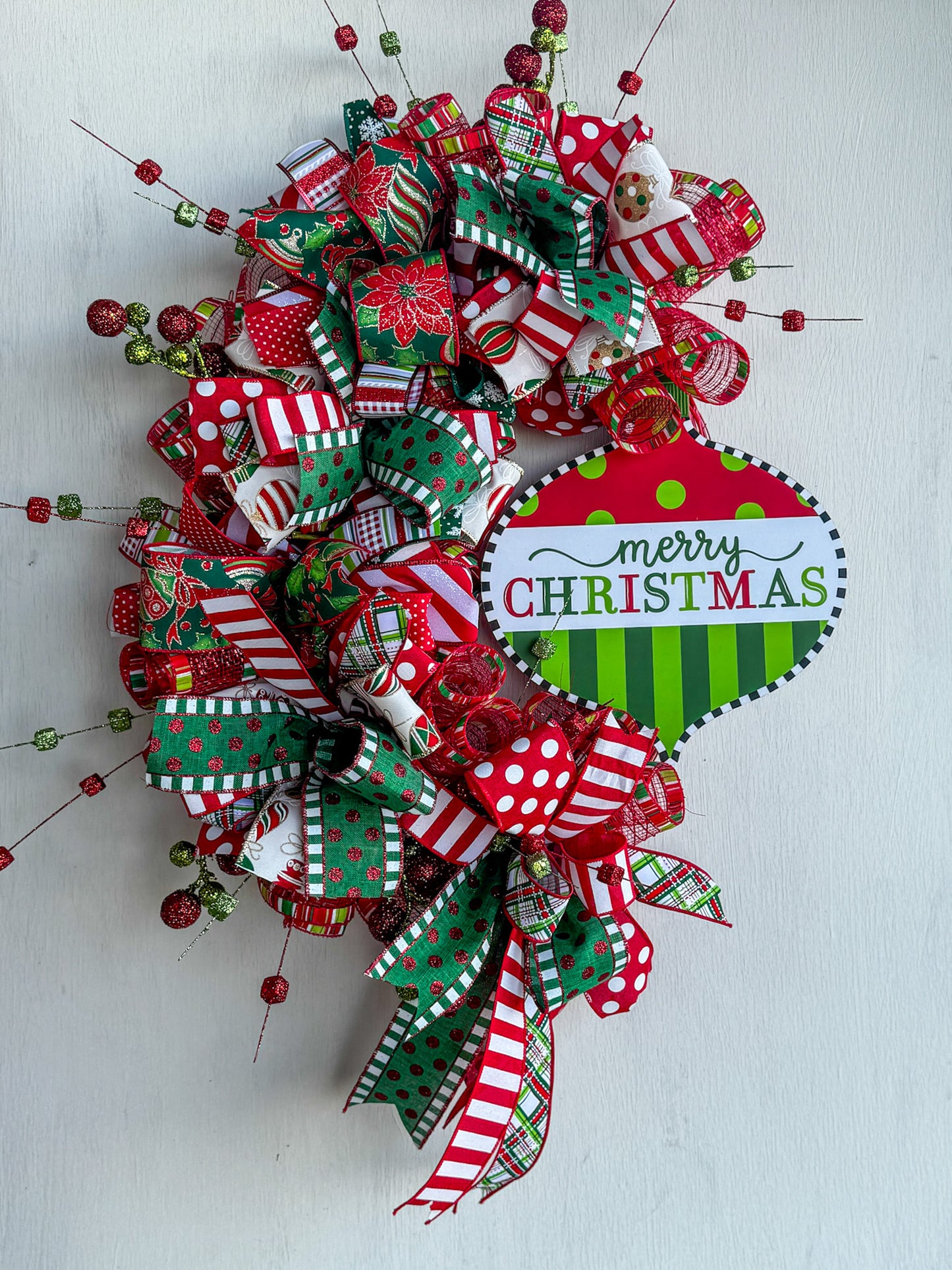 A joyful burst of color and Christmas cheer! This handcrafted Candy Stripe Grapevine Wreathfeatures layers of designer ribbon, sparkling accents, and a festive “Merry Christmas” sign — perfect for welcoming guests this holiday season.