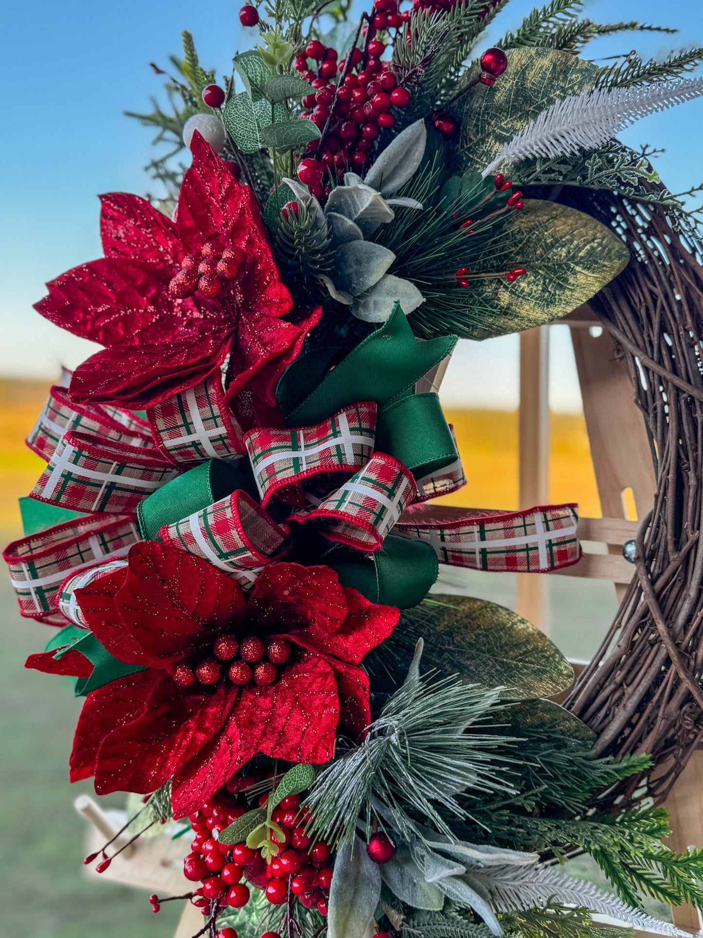 Two Poinsettia Christmas Grapevine Wreath: Traditional Christmas beauty with a touch of handcrafted grace โ this Two Poinsettia Grapevine Wreath features vibrant red poinsettias, lush greenery, and layered plaid ribbons in rich holiday tones.