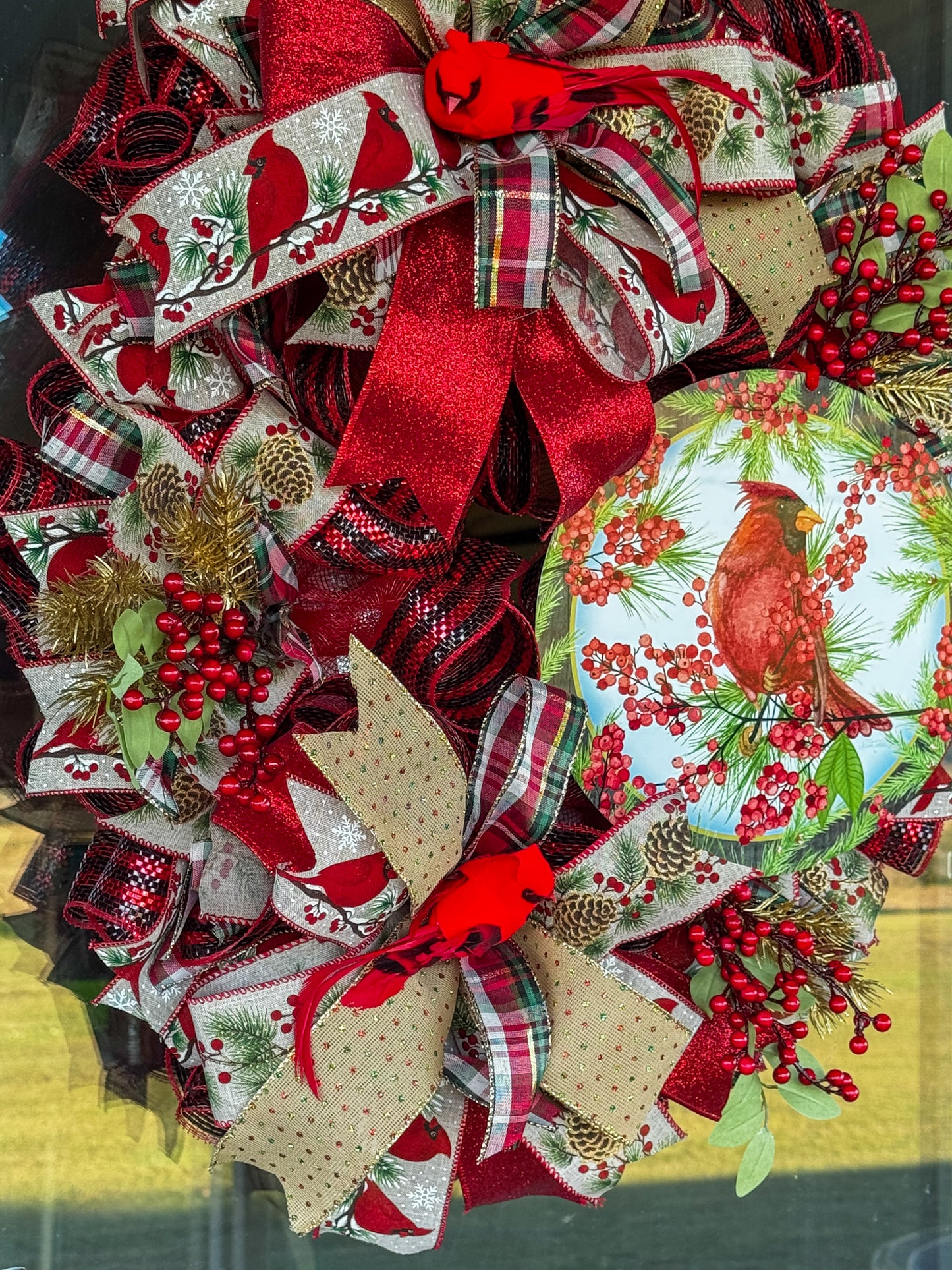 A symbol of hope and faith, this handcrafted cardinal wreath captures the beauty of Christmas with layered plaid ribbons, berry sprigs, and a vibrant cardinal centerpiece.