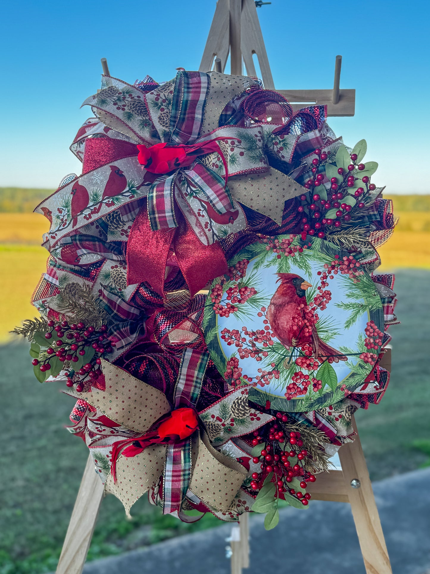 A symbol of hope and faith, this handcrafted cardinal wreath captures the beauty of Christmas with layered plaid ribbons, berry sprigs, and a vibrant cardinal centerpiece.