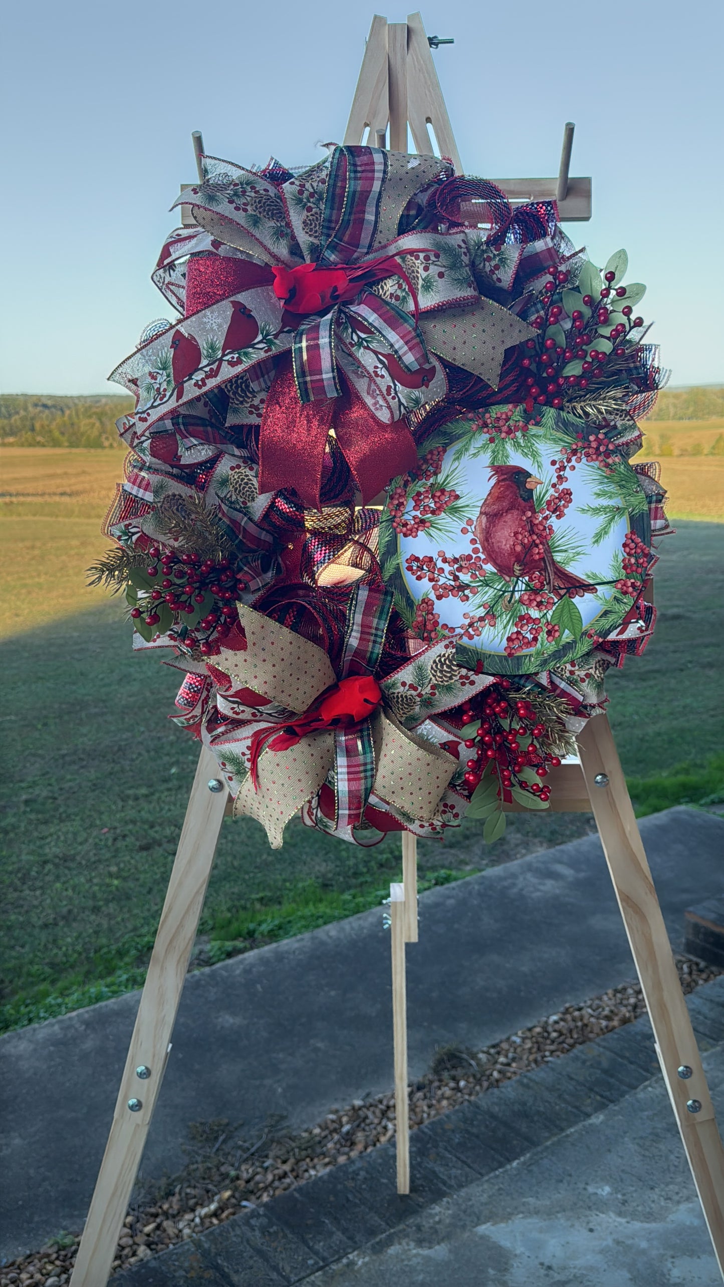 A symbol of hope and faith, this handcrafted cardinal wreath captures the beauty of Christmas with layered plaid ribbons, berry sprigs, and a vibrant cardinal centerpiece.
