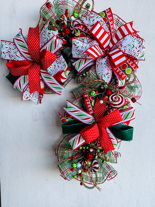 Whimsical handcrafted Candy Cane Swag with striped ribbon, glitter curls, and festive holiday accents. Playful, faith-inspired Christmas décor by Davis Wreath Creations.
