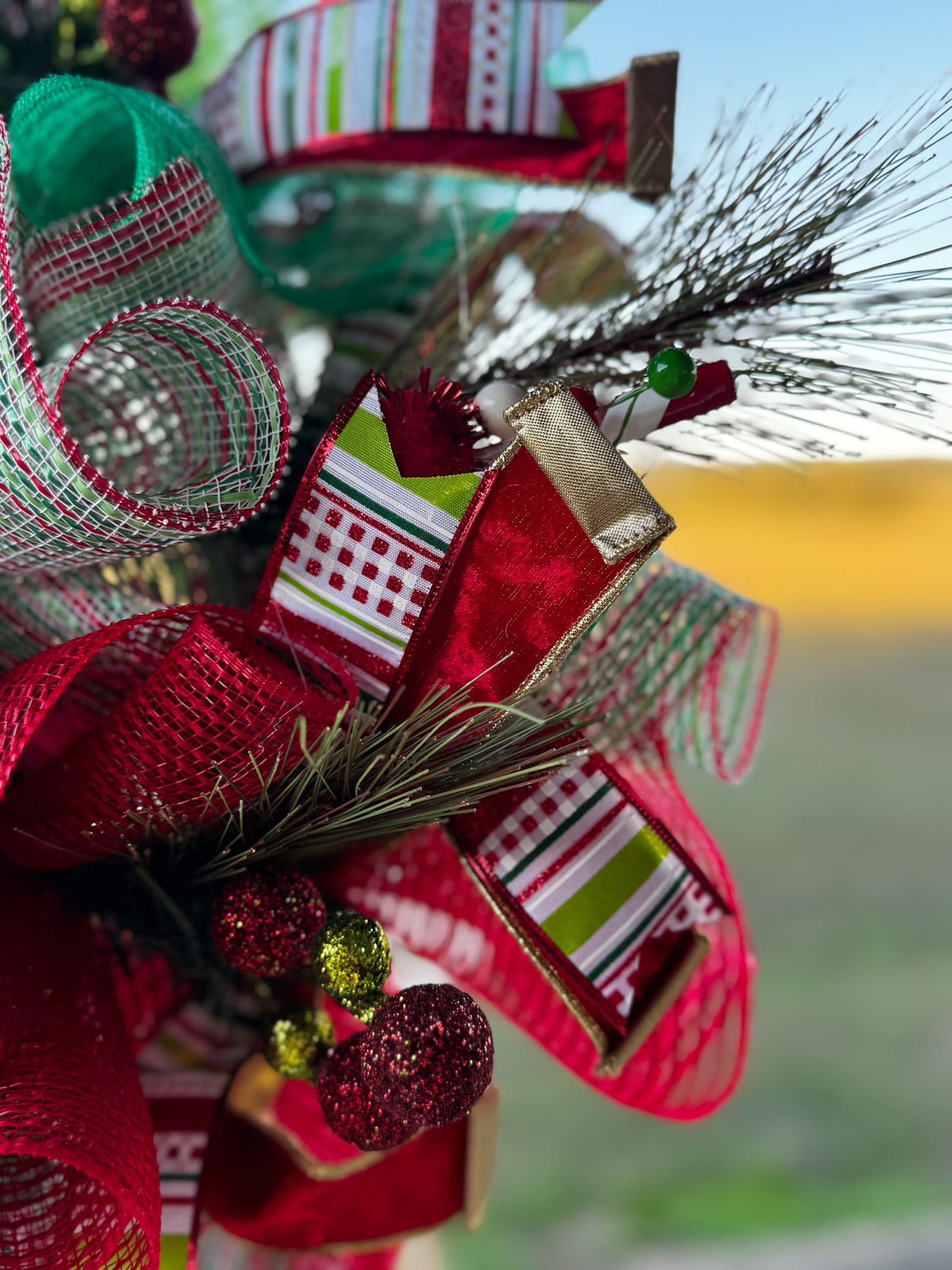 A burst of Christmas cheer! This Peppermint Twist Wreath blends playful red, green, and white ribbons with sparkling ornaments and a festive “Merry Christmas” sign — handcrafted to bring joy and color to your holiday door