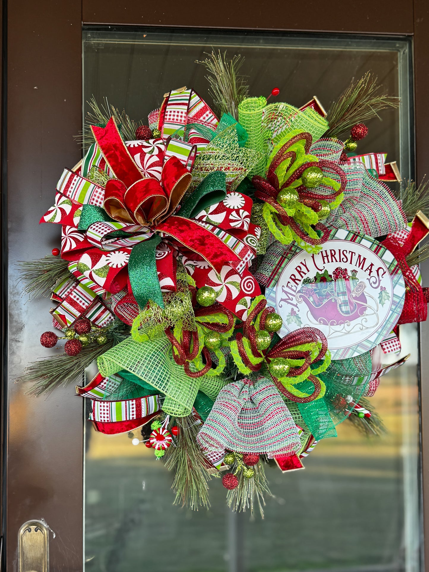 A burst of Christmas cheer! This Peppermint Twist Wreath blends playful red, green, and white ribbons with sparkling ornaments and a festive “Merry Christmas” sign — handcrafted to bring joy and color to your holiday door