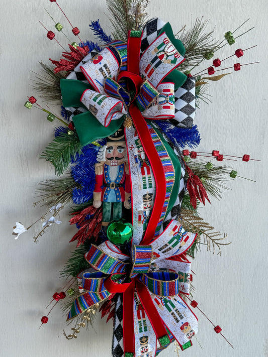 🎄 Nutcracker Teardrop Swag : A statement piece of Christmas elegance — this handcrafted Nutcracker swag blends classic charm with rich emerald velvet, harlequin ribbons, and glittering holiday details.