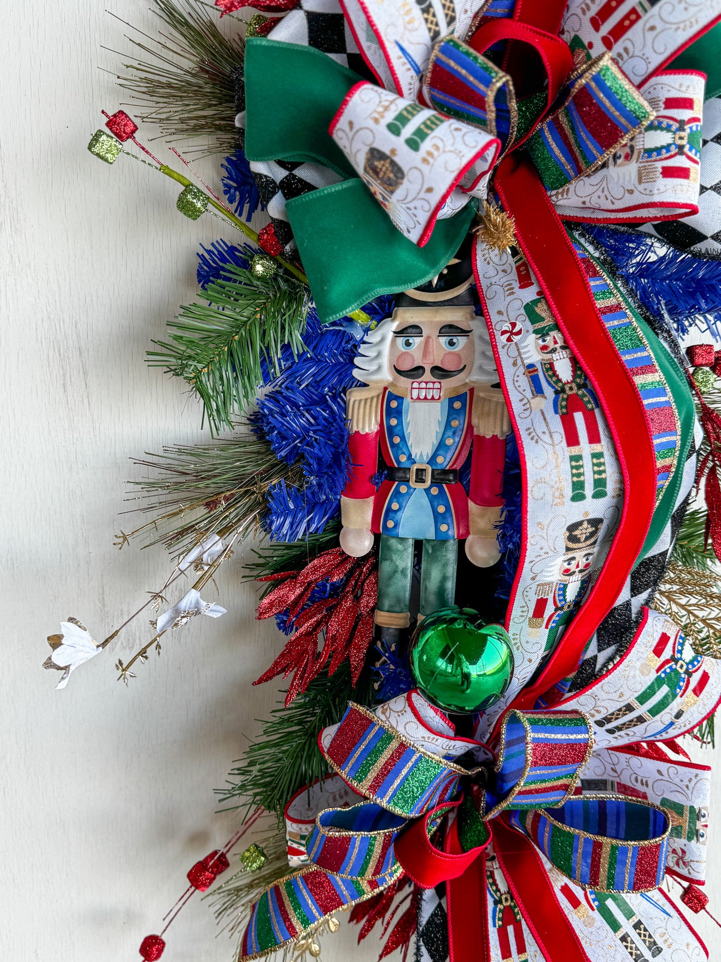 🎄 Nutcracker Teardrop Swag : A statement piece of Christmas elegance — this handcrafted Nutcracker swag blends classic charm with rich emerald velvet, harlequin ribbons, and glittering holiday details.