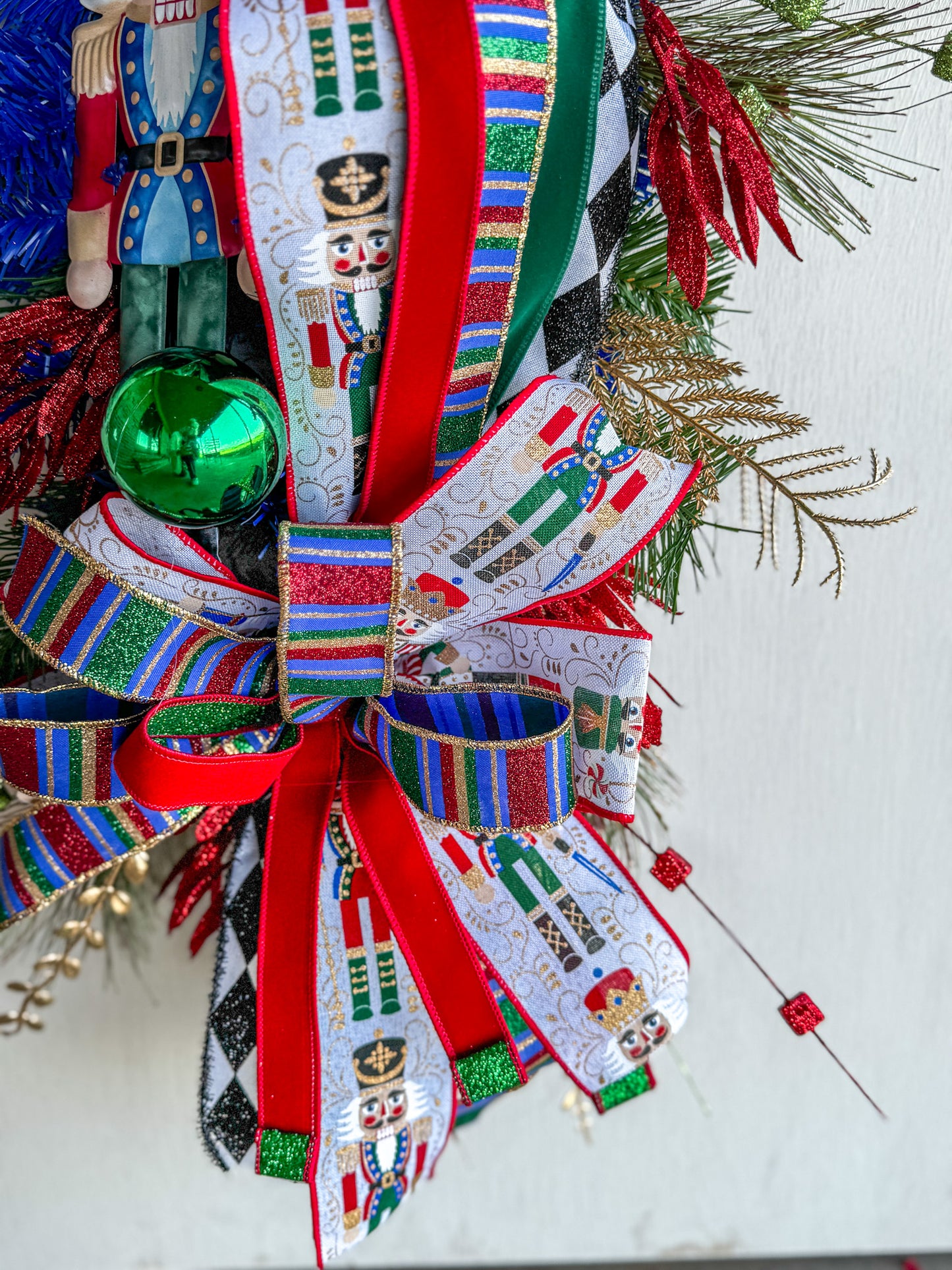 🎄 Nutcracker Teardrop Swag : A statement piece of Christmas elegance — this handcrafted Nutcracker swag blends classic charm with rich emerald velvet, harlequin ribbons, and glittering holiday details.